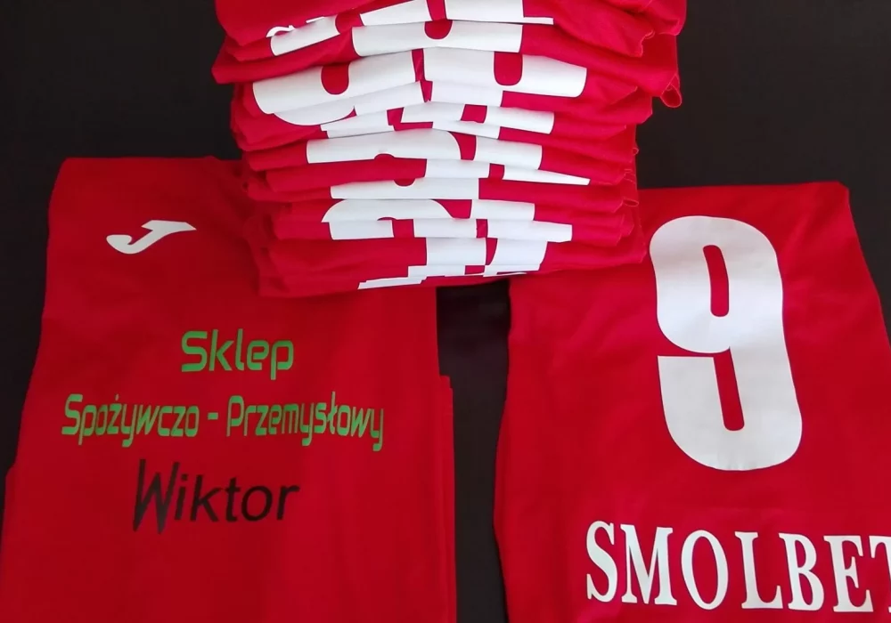 Czerwone koszulki piłkarskie z białymi numerami i nadrukiem